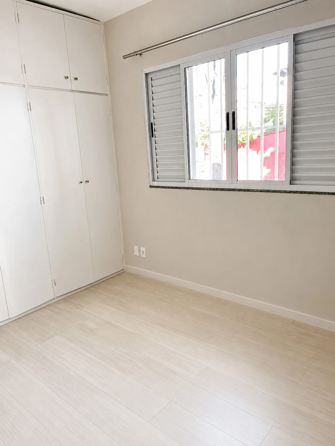 Quarto com armários embutidos brancos, piso claro e circulação para os demais ambientes.